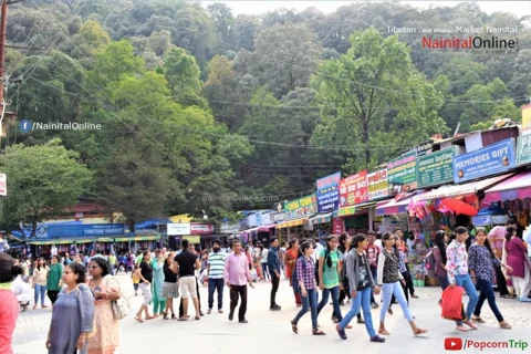 Shops and visitors at Tibetan Market beneath wooded Nainital hills